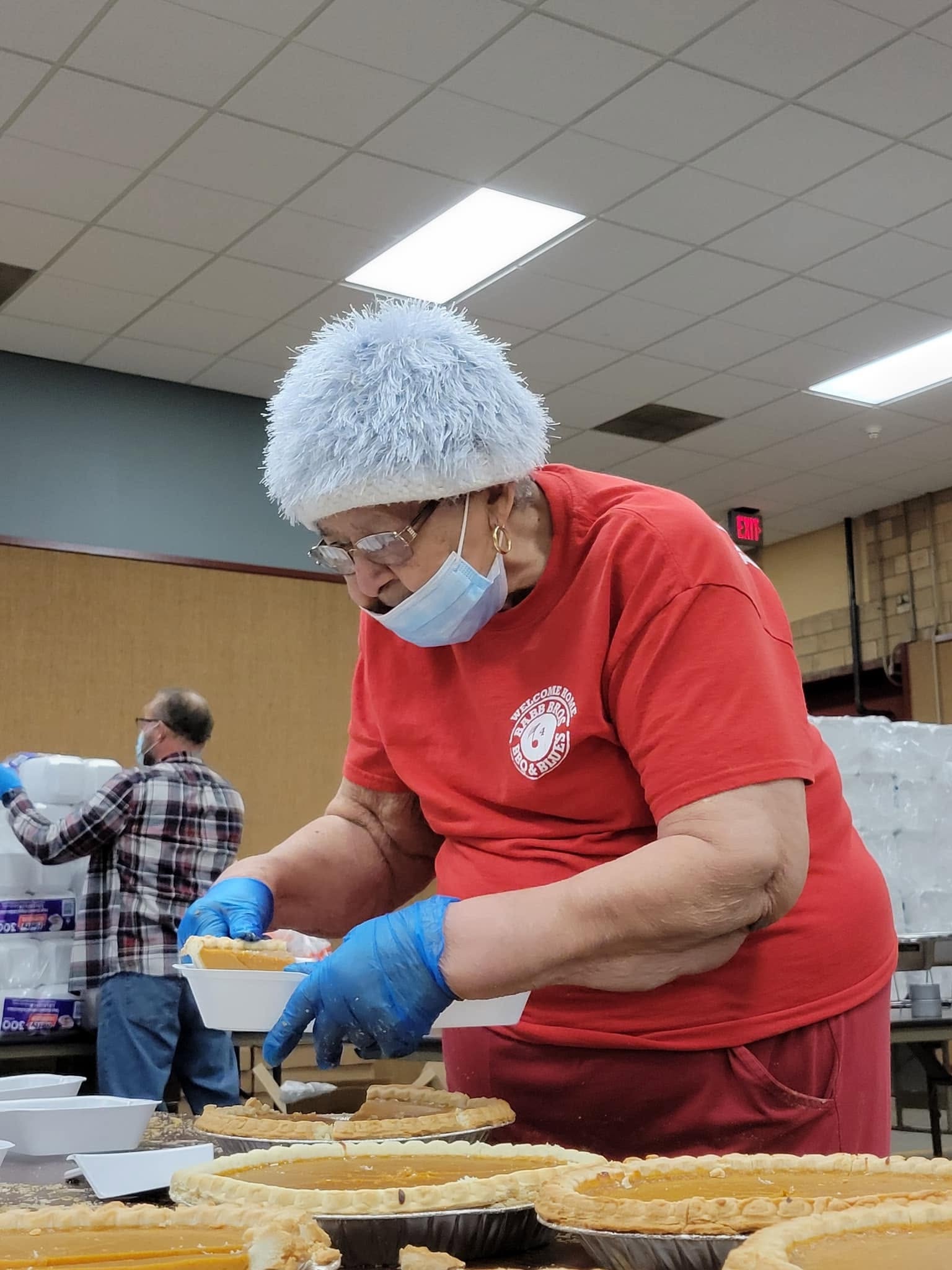 A volunteer portioning pies into meal containers.
